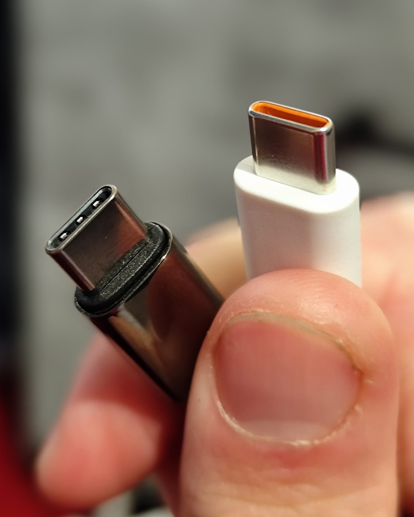 Close-up of two USB-C plugs held between a thumb and forefinger.