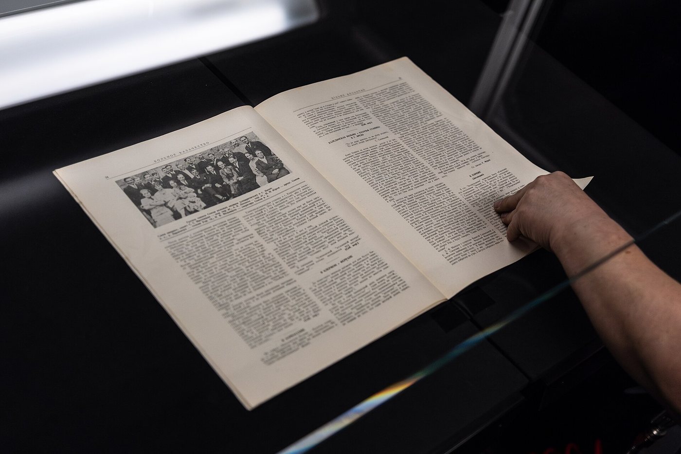 Une main tient ouvert un livre imprimé sur un numériseur manuel, pendant la numérisation à la Bibliothèque nationale de la République tchèque.